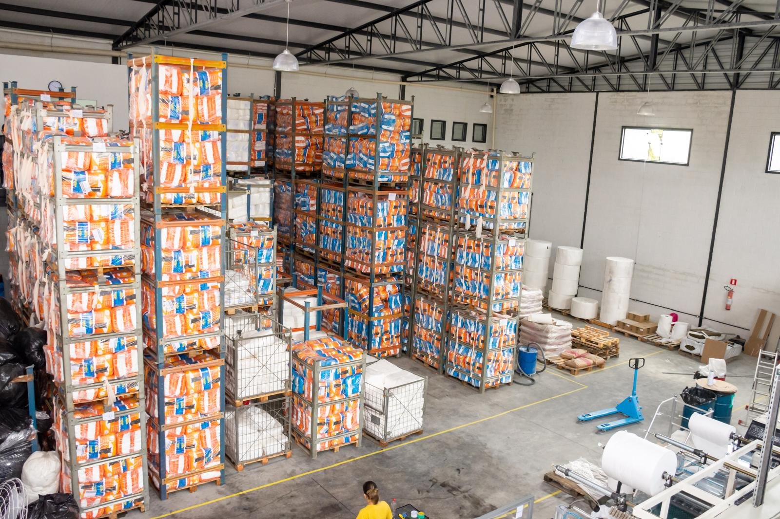 Estoque de tapetes higiênicos em paletes prontos para distribuição no atacado